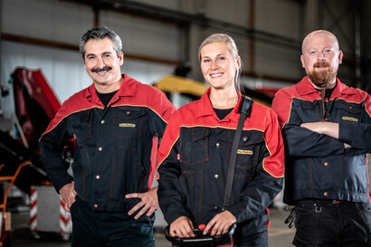 Zwei männliche und eine weibliche Mitarbeitende aus dem Qualitätsmanagement lächeln in die Kamera.