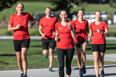 Eine Gruppe von PALFINGER Mitarbeitenden laufen im Grünen.