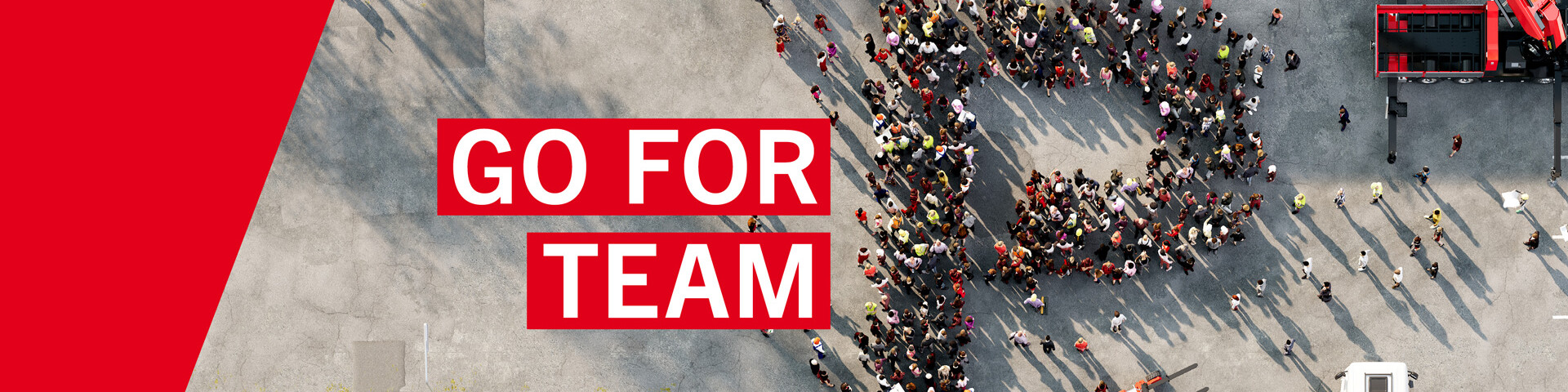 Може да се види претенцията „Go for Team P“. Служители стоят на паркинг и образуват буквата П. До тях стоят кран и мотокар. Може да се види претенцията „Go for Team P“. Служители стоят на паркинг и образуват буквата П. До тях стоят кран и мотокар.