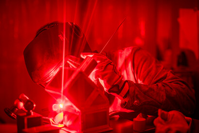 A metal welder works on a workpiece.