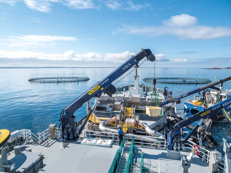 A PALFINGER worker is seen who is loading some stuff with a PALFINGER Marine crane on a boat.